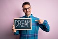 Young handsome man holding blackboard with dream message over pink background with surprise face pointing finger to himself Royalty Free Stock Photo