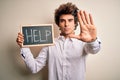 Young handsome man holding blackboard with help message over isolated white background with open hand doing stop sign with serious Royalty Free Stock Photo