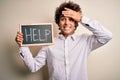 Young handsome man holding blackboard with help message over isolated white background stressed with hand on head, shocked with Royalty Free Stock Photo