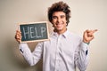 Young handsome man holding blackboard with help message over isolated white background very happy pointing with hand and finger to Royalty Free Stock Photo