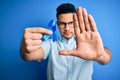 Young handsome man holding blue cancer ribbon standing over isolated background with open hand doing stop sign with serious and Royalty Free Stock Photo