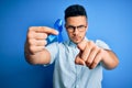 Young handsome man holding blue cancer ribbon standing over isolated background pointing with finger to the camera and to you,