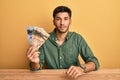 Young handsome man holding canadian dollars relaxed with serious expression on face Royalty Free Stock Photo