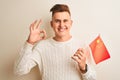 Young handsome man holding Chinese China flag over isolated white background doing ok sign with fingers, excellent symbol Royalty Free Stock Photo