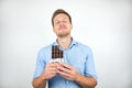 Young handsome man holding chocolate bar looking pleased on  white background Royalty Free Stock Photo