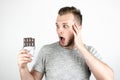 Young handsome man holding chocolate bar looking surprised on isolated white background Royalty Free Stock Photo