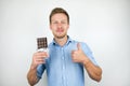 Young handsome man holding chocolate bar showing like sign on  white background Royalty Free Stock Photo