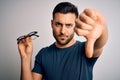 Young handsome man holding correction eye glasses over isolated background with angry face, negative sign showing dislike with Royalty Free Stock Photo