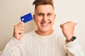 Young handsome man holding credit card over isolated white background pointing and showing with thumb up to the side with happy Royalty Free Stock Photo