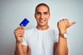 Young handsome man holding credit card over white isolated background pointing and showing with thumb up to the side with happy Royalty Free Stock Photo