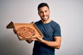 Young handsome man holding delivery box with delicious Italian pizza over white background with a happy face standing and smiling Royalty Free Stock Photo