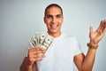 Young handsome man holding dollars over white isolated background very happy and excited, winner expression celebrating victory Royalty Free Stock Photo