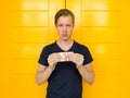 Young handsome man holding 10 euro in front of yellow door Royalty Free Stock Photo