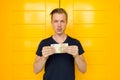 Young handsome man holding 50 euro in front of yellow door Royalty Free Stock Photo