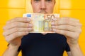 Young handsome man holding 50 euro in front of yellow door Royalty Free Stock Photo