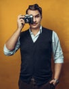 Young Handsome Man Holding Film Camera Near Face, Portrait On Yellow Background