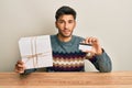 Young handsome man holding gift and credit card relaxed with serious expression on face Royalty Free Stock Photo