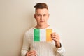 Young handsome man holding Ireland Irish flag over isolated white background with a confident expression on smart face thinking Royalty Free Stock Photo