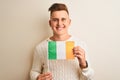 Young handsome man holding Ireland Irish flag over isolated white background with a happy face standing and smiling with a Royalty Free Stock Photo