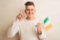 Young handsome man holding Ireland Irish flag over isolated white background surprised with an idea or question pointing finger Royalty Free Stock Photo