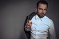 Young handsome man holding a jacket posing isolated over gray background. Royalty Free Stock Photo