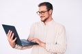 Young handsome man holding laptop looking positive and happy standing and smiling with a confident smile showing teeth Royalty Free Stock Photo