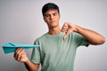 Young handsome man holding paper airplane over isolated white background with angry face, negative sign showing dislike with Royalty Free Stock Photo