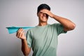 Young handsome man holding paper airplane over isolated white background stressed with hand on head, shocked with shame and Royalty Free Stock Photo