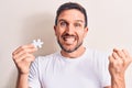 Young handsome man holding piece of puzzle standing over isolated white background screaming proud, celebrating victory and Royalty Free Stock Photo