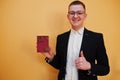 Young handsome man holding Portuguese Republic passport id over yellow background, happy and show thumb up. Travel to Europe