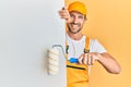 Young handsome man holding roller painter over white banner smiling with a happy and cool smile on face