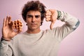 Young handsome man holding sweet waffle standing over isolated pink background with angry face, negative sign showing dislike with