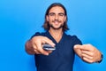 Young handsome man holding television remote control smiling happy pointing with hand and finger Royalty Free Stock Photo