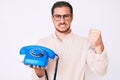 Young handsome man holding vintage telephone annoyed and frustrated shouting with anger, yelling crazy with anger and hand raised Royalty Free Stock Photo