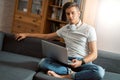 Young handsome man with laptop on gray sofa at home