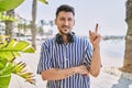 Young handsome man listening to music using headphones outdoors with a big smile on face, pointing with hand and finger to the Royalty Free Stock Photo