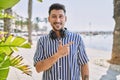 Young handsome man listening to music using headphones outdoors cheerful with a smile of face pointing with hand and finger up to Royalty Free Stock Photo