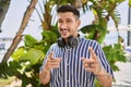 Young handsome man listening to music using headphones outdoors pointing fingers to camera with happy and funny face Royalty Free Stock Photo