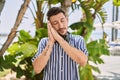 Young handsome man listening to music using headphones outdoors sleeping tired dreaming and posing with hands together while Royalty Free Stock Photo