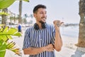 Young handsome man listening to music using headphones outdoors smiling with happy face looking and pointing to the side with Royalty Free Stock Photo