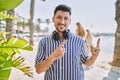 Young handsome man listening to music using headphones outdoors smiling and looking at the camera pointing with two hands and Royalty Free Stock Photo