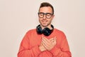 Young handsome man listening to music using headphones over isolated white background smiling with hands on chest with closed eyes Royalty Free Stock Photo