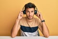 Young handsome man listening to music wearing headphones relaxed with serious expression on face Royalty Free Stock Photo