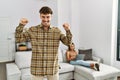 Young handsome man at the living room with girlfriend very happy and excited doing winner gesture with arms raised, smiling and Royalty Free Stock Photo