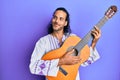 Young handsome man with long hair playing classical guitar smiling looking to the side and staring away thinking Royalty Free Stock Photo