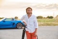 A young handsome man with long hair stands with a tripod somewhere on a country road, the photographer artist arrived in Royalty Free Stock Photo