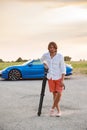 A young handsome man with long hair stands with a tripod somewhere on a country road, the photographer artist arrived in Royalty Free Stock Photo