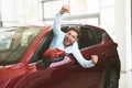 Young handsome man looking for new car in dealership center sticking out the vehicle window happily Royalty Free Stock Photo