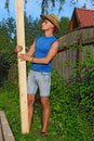 Young handsome man looks at a pine Board in the hands of about a