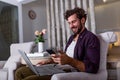 Young handsome man making video call with friends while sitting on sofa at his modern home.Concept of happy business people. Royalty Free Stock Photo
